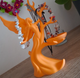 Orange tree-shaped jewelry holder with necklaces on a wooden surface.